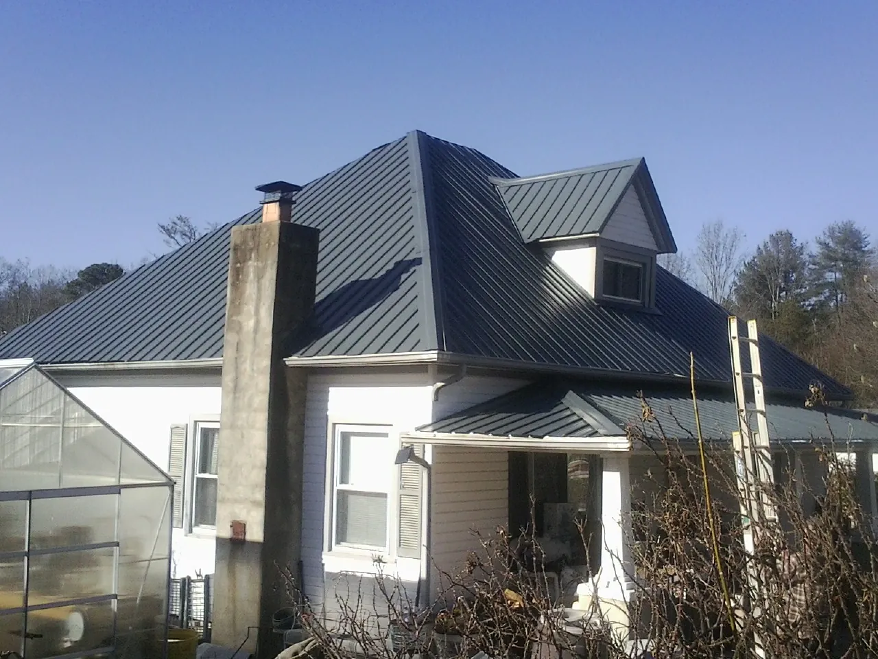 Dark blue standing seam metal roof on a white farmhouse with dormer — Slate & Tile Roof Repair by Roofing Brothers in Gibsonburg