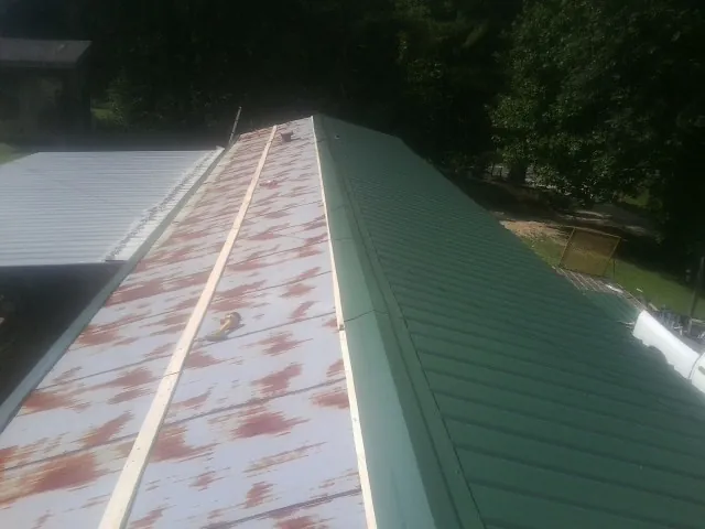 Old rusted panels beside newly installed green metal roofing — Wind Damage Roof Repair by Roofing Brothers in Gibsonburg