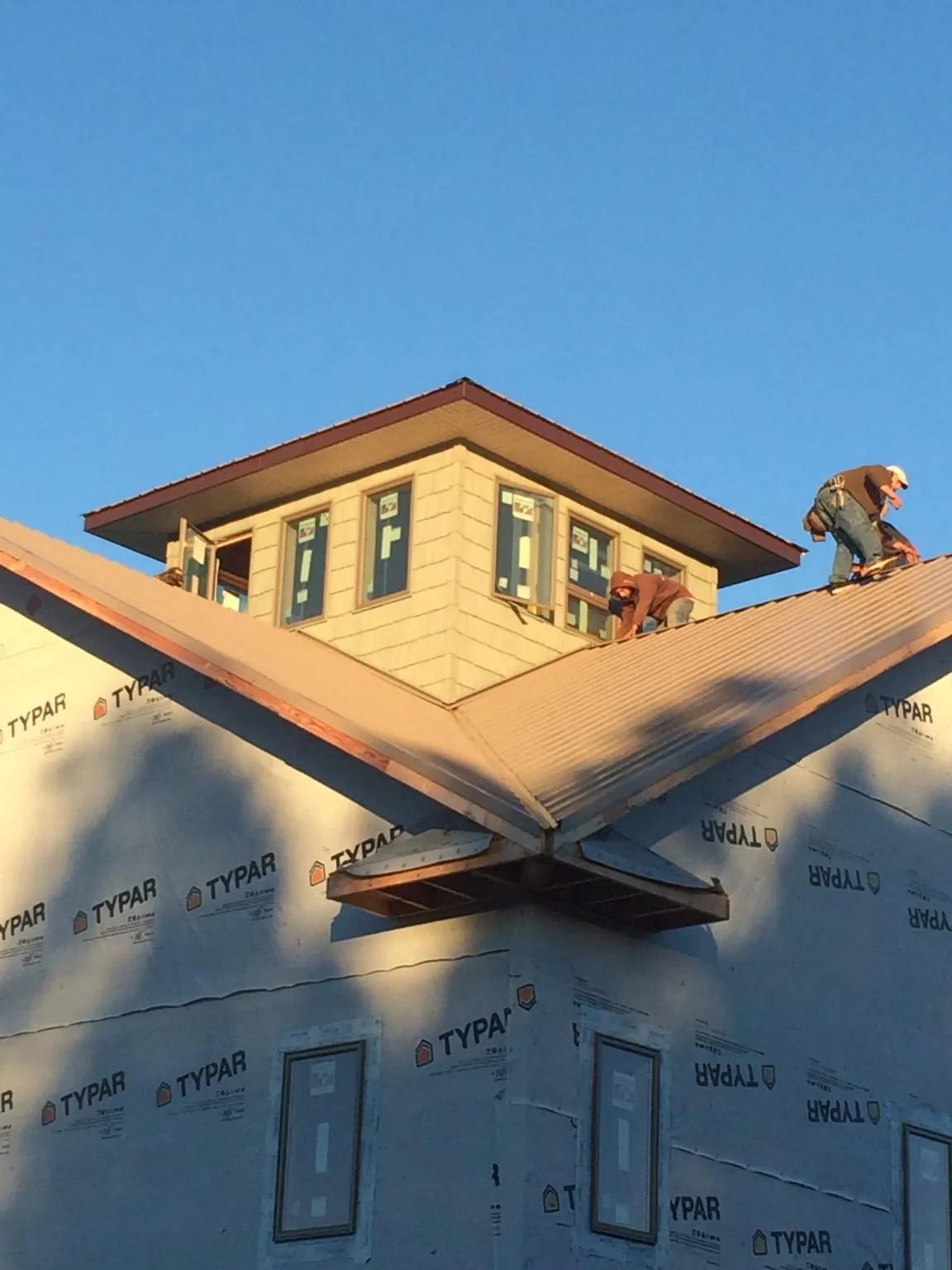 Roofers working around a rooftop cupola on a new metal roof at sunset — Roof Waterproofing in Gibsonburg by Roofing Brothers